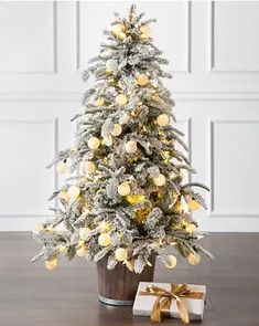 a white christmas tree with yellow balls and lights