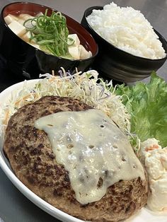 a white plate topped with meat covered in gravy next to rice and salad