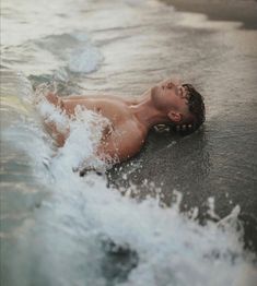 a shirtless man swimming in the ocean