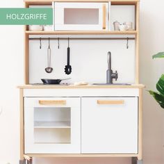 a white and wooden kitchen with pots, pans and utensils on the shelves