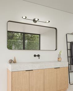 a bathroom with a large mirror above the sink and wooden cabinets below it, along with a towel rack