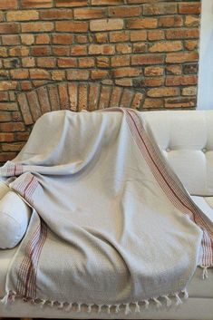 a white couch sitting next to a brick wall with a blanket on top of it