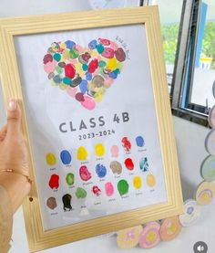 a person holding up a framed art piece with the words class 4b on it