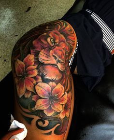 a lion and flowers tattoo on the leg of a person's leg, next to a black leather couch