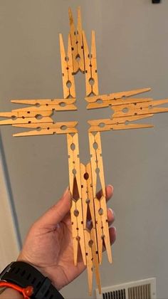 a person holding up a wooden cross made out of clothes pins