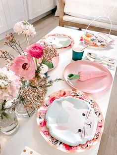 the table is set with pink plates and flowers