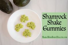 shamrock shaped cookies on a white plate next to avocados and a green sign