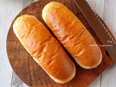 two loaves of bread sitting on top of a cutting board next to a knife