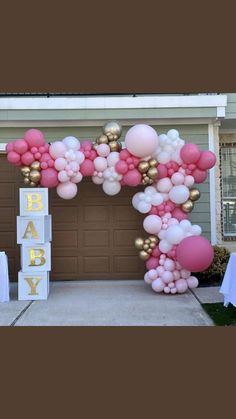 a pink and gold balloon arch for a baby shower