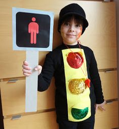 a young boy wearing a costume made to look like a traffic light and holding a sign