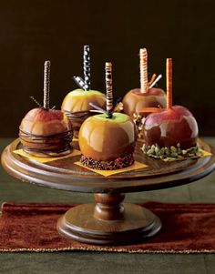 an image of apples and caramels on a cake plate with candles in them