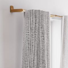 a curtain hanging on the side of a white wall next to a gold towel rack