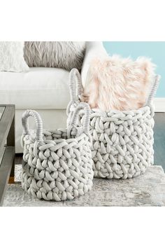 two woven baskets sitting on top of a rug in front of a white couch and coffee table