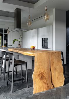 a large wooden table sitting in the middle of a kitchen next to two bar stools