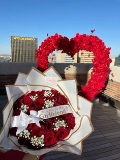 a bouquet of red roses in front of a heart shaped wreath on top of a building