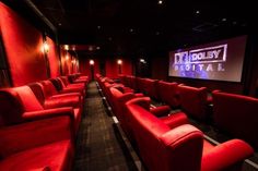 an empty theater with red seats and a projector screen in the center is lit up