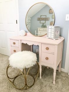 a pink vanity with a mirror and stool in front of it on carpeted floor