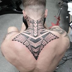 a man with a tattoo on his back is sitting down and looking at the camera