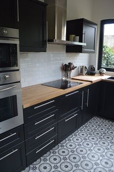 a kitchen with black cabinets and stainless steel appliances