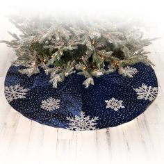 a christmas tree skirt with snowflakes and lights on it, sitting on a wooden floor