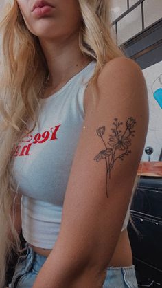 a woman with a flower tattoo on her left arm and right arm behind her back