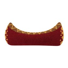 a red and gold knitted pillow sitting on top of a white wall