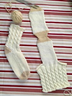 two white knitted mittens with yarn and knitting needles