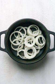 onions are being cooked in a skillet on a white table top with a spoon