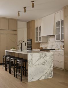 a large kitchen with marble counter tops and wooden flooring, along with bar stools