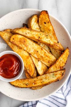 french fries on a plate with ketchup in a small bowl next to them