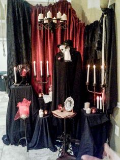 a display with candles and cloths in front of a red curtain