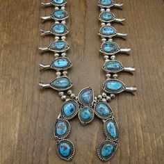 "Sterling silver and turquoise squash blossom necklace. This necklace is 27\" long. The naja is 3 1/2\" tall x 3\" wide. There are 8 turquoise stones on the naja. It is signed Tony Garcia on the back. The silver beads are 8mm in diameter. Each side has 6 blossoms which are from 1 5/8 to 1 3/4\" long. The bezel set stones are surrounded by twisted wire rope. One side has a silver bead edge. On the other side a silver wire with a loop on the top and bottom. The stones in the two blossoms closest t Western Blue Jewelry For Western-themed Events, Southwestern Blue Jewelry For Western-themed Events, Blue Western Style Jewelry With Inlay, Western Style Blue Turquoise Collectible Necklace, Turquoise Squash Blossom, Squash Blossom Necklace, Silver Eagles, Squash Blossom, Twisted Wire