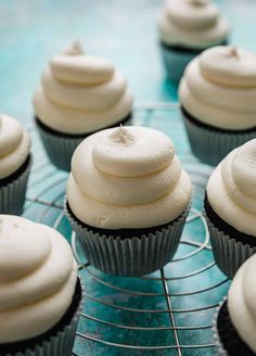 white frosted cream frosting on top of cupcakes cooling on a wire rack