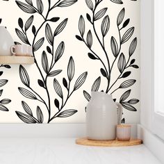 the wallpaper is decorated with black leaves on white walls and shelves in front of it