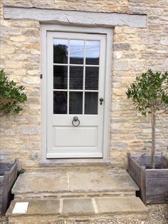 a white front door with two planters on either side and one tree in the middle