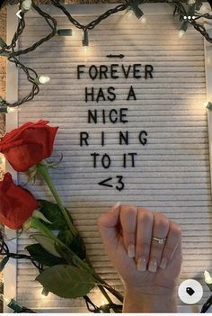 a person holding a rose in front of a sign that says forever has a nice ring to it