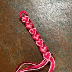 a pink and white piece of string on a table with a red cord attached to it