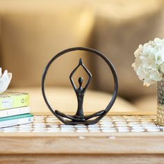 a table topped with a vase filled with flowers next to a metal figure on top of a