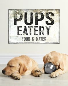 two dogs laying on the floor next to a sign that says pups eatery