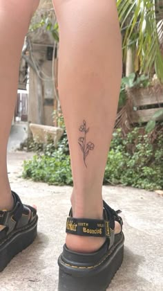 a woman's foot with a small flower tattoo on her left leg and the words,