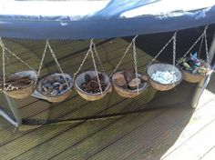 several baskets filled with different types of rocks on a wooden deck, hanging from chains