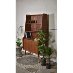 an old wooden bookcase with plants in pots on the floor next to potted plants