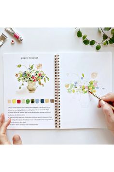 someone is painting flowers in a book with watercolors