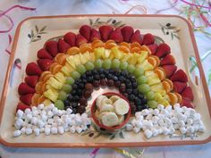 a platter with fruit and marshmallows arranged in the shape of a rainbow