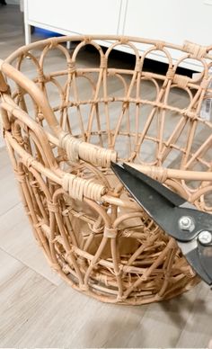 a pair of scissors sitting inside of a wicker basket on top of tile flooring