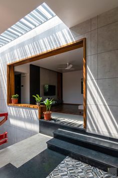 the sun shines through an open window onto a room with stairs and potted plants