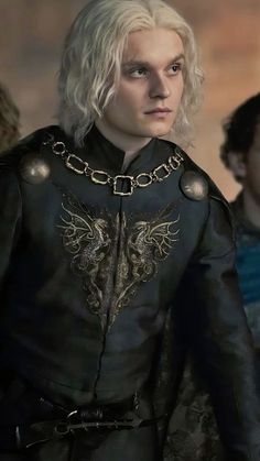 the white haired man is dressed in black leather and has gold accents on his chest