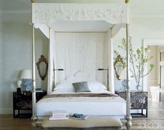 a white bed sitting in a bedroom next to two tables