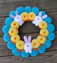 an easter wreath made out of pom poms and stuffed animals sits on a wooden surface