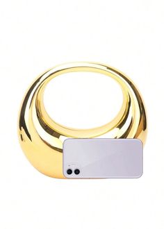 an electronic device is sitting on top of a gold ring with a white button in the middle